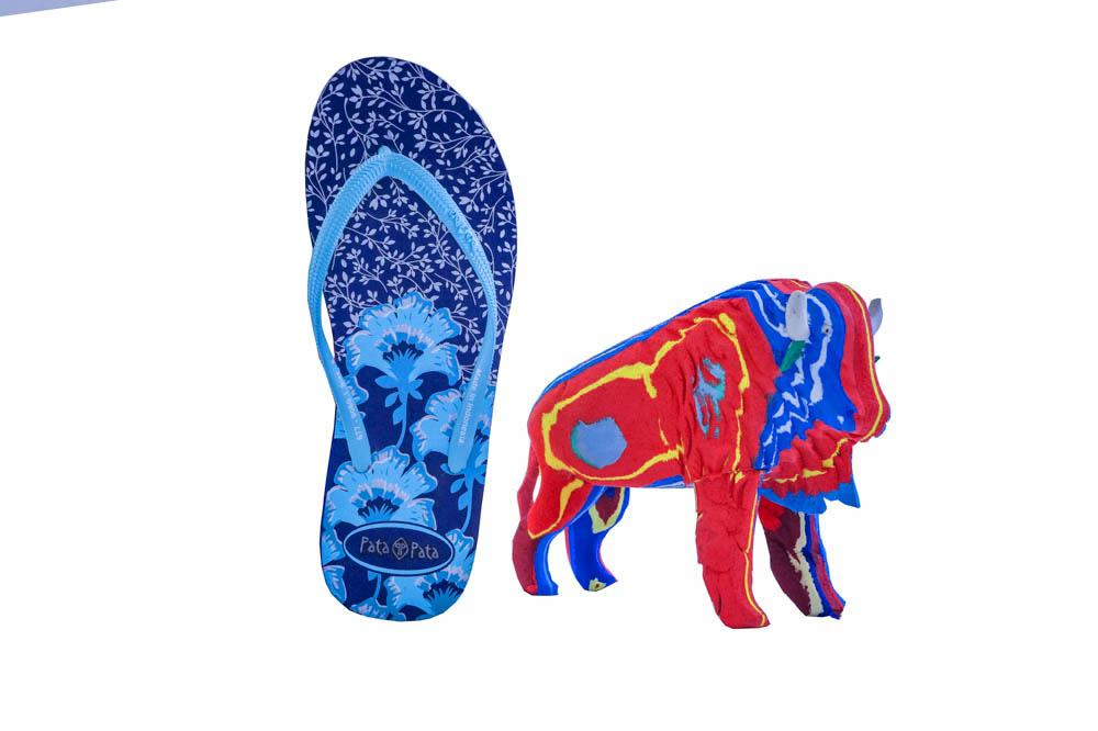 Hand-carved multicolored bison sculpture made of upcycled flip flops by Ocean Sole in size comparison to a flip flop.