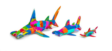 Three hand-carved multicolored hammerhead shark sculptures made of upcycled flip flops by Ocean Sole in size comparison.