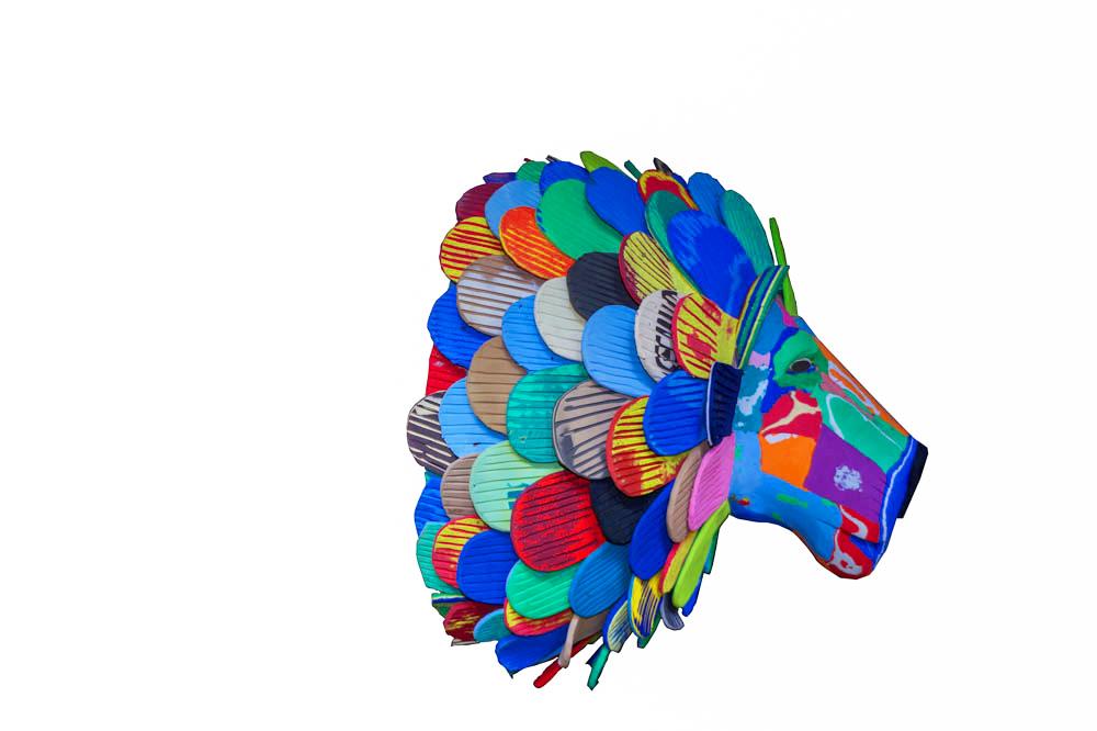 Hand-carved multicolored lion wall art sculpture made of upcycled flip flops by Ocean Sole designed to hang on your wall.