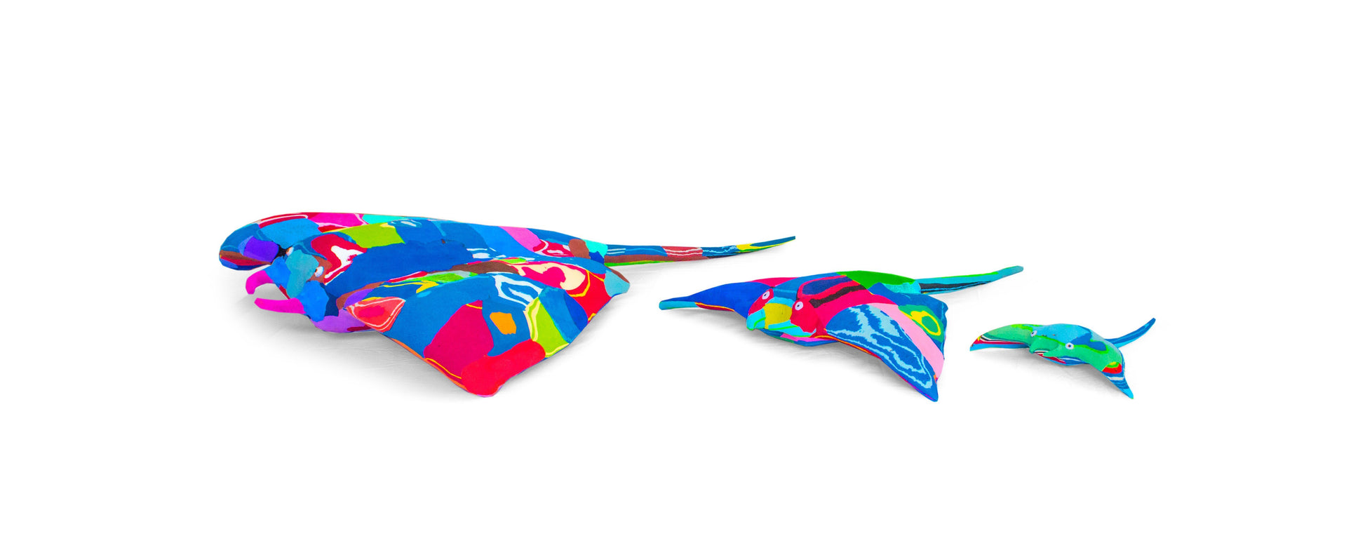 Three hand-carved multicolored manta ray sculptures made of upcycled flip flops by Ocean Sole lined up in size comparison.