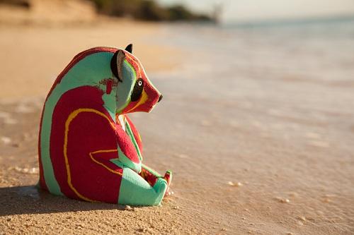 Hand-carved multicolored panda sculpture made of upcycled flip flops by Ocean Sole sitting on a beach.