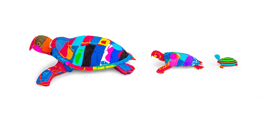 Three hand-carved multicolored turtles sculpture made of upcycled flip flops by Ocean Sole lined up in size comparison.