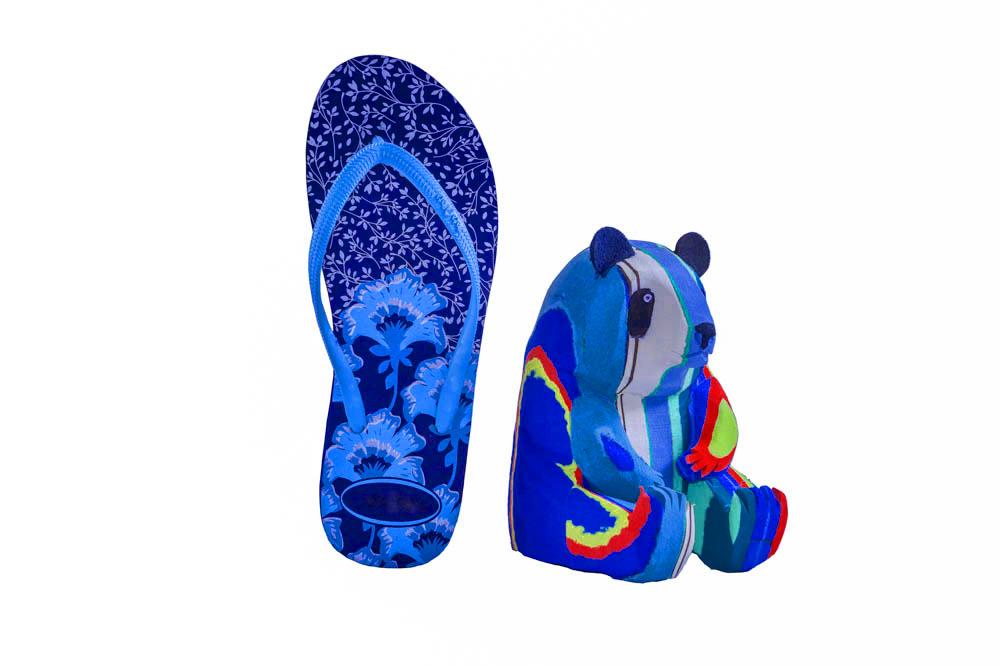 Hand-carved multicolored panda sculpture made of upcycled flip flops by Ocean Sole in size comparison to a flip flop.