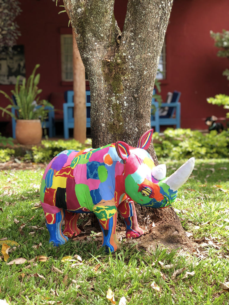 Hand-carved multicolored rhino sculpture made of upcycled flip flops by Ocean Sole sitting outside in the backyard.