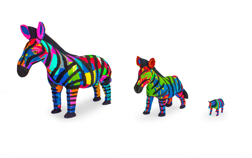 Three hand-carved multicolored zebra sculptures made of upcycled flip flops by Ocean Sole lined up in size comparsion.